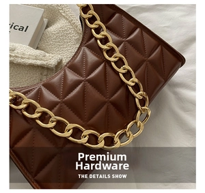 Detail of high-quality gold metal chain strap and brown quilted leather on baguette bag