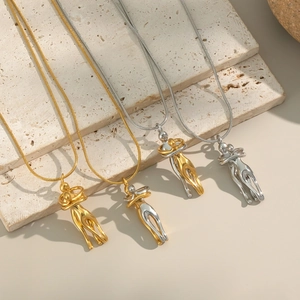 Waterproof gold and silver hug pendant necklaces displayed on a minimalist stone base