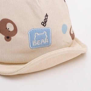 Macro shot of beige corduroy baby hat with cute bear embroidery and blue polka dots
