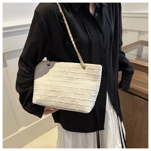 Detail of white tweed tote bag featuring gold chain and woven leather shoulder strap