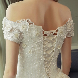 Dettaglio posteriore dell'abito da sposa con corsetto stringato e ricami floreali in rilievo