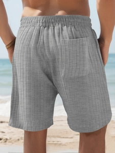Detail of grey striped knit fabric and elastic waist on men's beach shorts outdoors