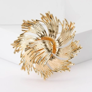 Vue détaillée d'une grande broche feu d'artifice dorée avec texture sur décor blanc