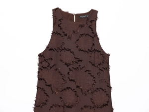 Détail du tissu texturé à franges et du col à boutons sur le haut marron sans manches