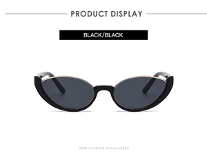 Detail view of black cat-eye sunglasses with gold metal top trim on a white background