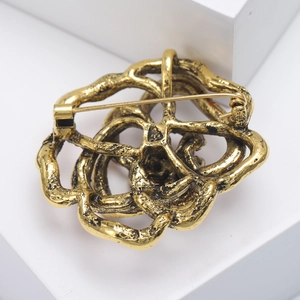 Detail view of the golden flower brooch back structure showing the pin and fastening clasp