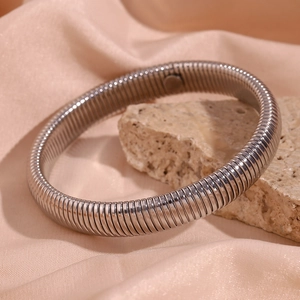 Détail du bracelet serpent argenté avec texture en spirale sur fond de soie et pierre brute