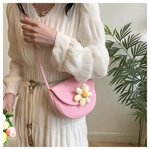 Dettaglio borsa a sella intrecciata rosa con margherita 3D e tracolla coordinata
