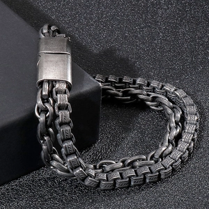 Macro detail of vintage industrial square link steel bracelet on minimalist black box