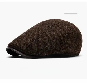 Detail of coffee color wool flat cap with tweed texture and leather brim accent