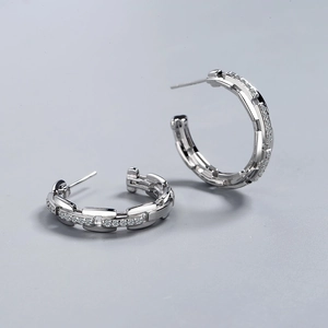 Silver C-shape hoop earrings with chain texture and zircon stones on gray background