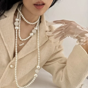 Elegant multi-layered pearl necklace worn with a beige tweed jacket and tulle gloves