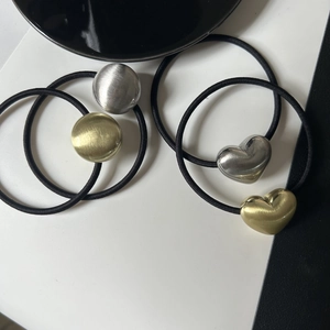 Close-up of four elastic hair ties with brushed gold and silver heart and round metal charms