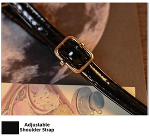 Detail of adjustable black patent leather shoulder strap with a gold metal buckle