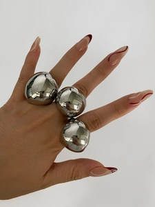 Three oversized polished silver steel chunky rings worn on a hand for a bold fashion look