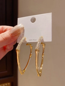 Detailed close-up of golden bamboo texture heart-shaped earrings with sparkling rhinestones