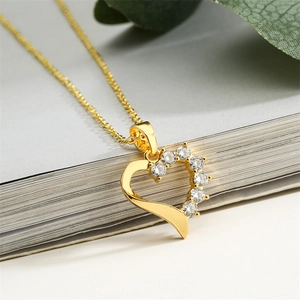 Macro shot of gold heart pendant with sparkling crystals and a smooth metal surface