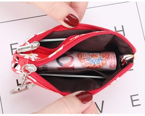Detail view of red daisy coin purse with dual zippers and key ring shown open