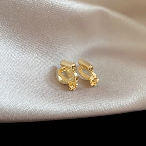 Close-up of golden clip-on earring converters with soft silicone pads on silk fabric