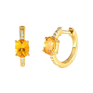 Macro shot of gold hoop earrings featuring a yellow gemstone and sparkling white zircons