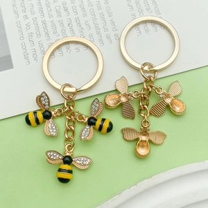 Detailed close-up of bee keychains with crystal-set wings and enamel honeycomb pendants