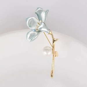 Detail of light blue enamel flower brooch with golden stem and elegant pearl accent