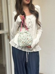 Detail of quilted drawstring bucket bag featuring floral pattern and pink rope handles