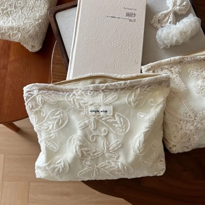 Détail de la broderie en dentelle crème élégante et texture florale du sac à cosmétiques
