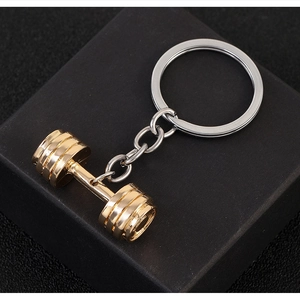 Detail of creative dumbbell keychain featuring a gold and silver metallic finish for fitness lovers