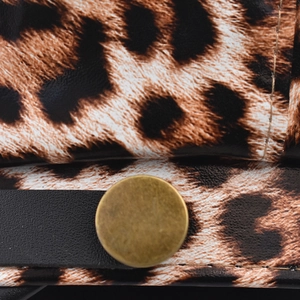 Macro detail of leopard print faux leather texture with bronze metal snap button
