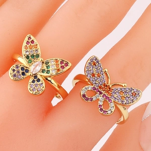 Macro shot of gold butterfly rings set with colorful pavé cubic zirconia on fingers