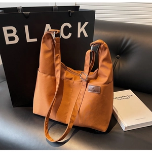 Detail of caramel orange nylon hobo bag featuring fashion label and adjustable silver buckle