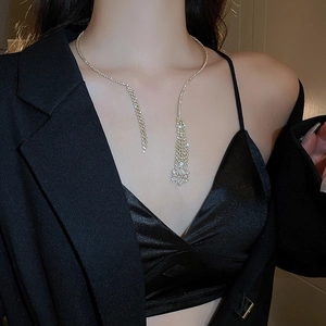 Detail shot of sparkling tassel rhinestone necklace on model with golden metal finish