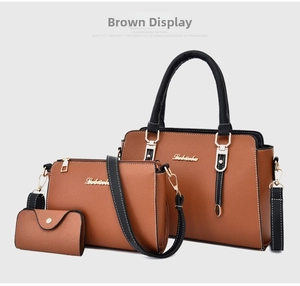Detail of three-piece tan leather handbag set with black handles and gold hardware