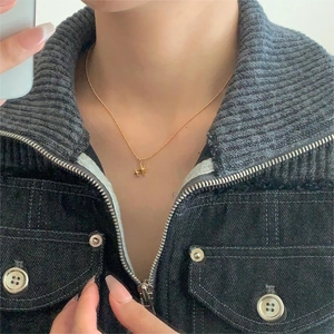Close-up of minimalist gold star pendant necklace worn over dark denim jacket