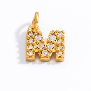 Macro shot of 18K gold plated letter M pendant encrusted with sparkling cubic zirconia