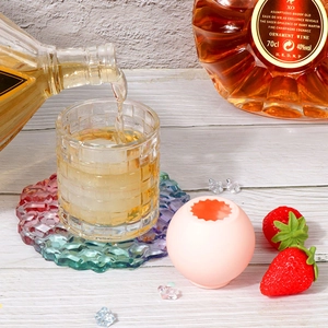 Rosa Silikonform für große Eiskugeln auf einem weißen Holztisch für Cocktails