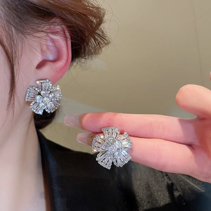 Vue détaillée de boucles d'oreilles fleurs argentées avec zircons étincelants sur l'oreille