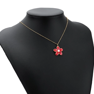 Golden necklace with red flower pendant and pearl center displayed on a black mannequin