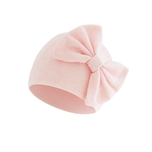 Close-up of baby beanie with soft knitted pink fabric and large decorative bow detail