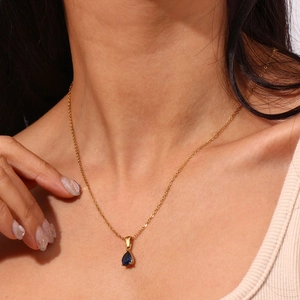 Gros plan d'un pendentif en zircon bleu sur une chaîne en acier inoxydable plaqué or 18K