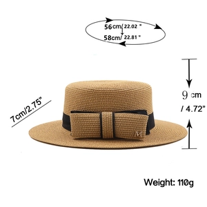 Close-up of brown straw hat weave with black ribbon and golden M buckle detail