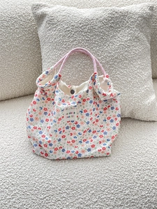 Detail of floral canvas tote bag showing pink handles and snap button closure