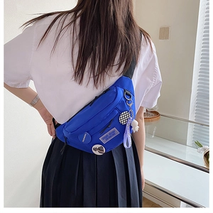 Detail of vibrant blue nylon chest bag with space-themed charms and multi-layer zippers