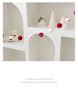 Close-up of red and white wool felt ball garland on a minimalist white Nordic shelf