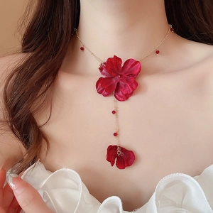 Detail of red fabric flower choker with golden chain and delicate tassel pendants