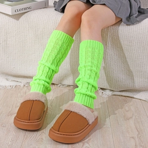 Detail of neon green cable knit leg warmers paired with brown plush platform slippers