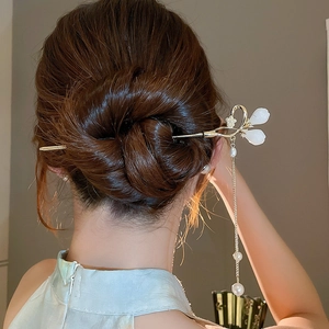 Détail de l'épingle à cheveux dorée avec pétales blancs et longs glands de perles