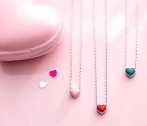 Macro shot of colorful enamel heart pendants on silver chains in pink and red