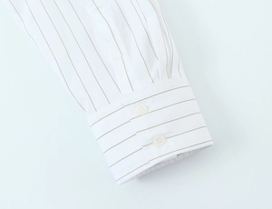 Detailed macro view of white cotton shirt cuff with brown stripes and double buttons